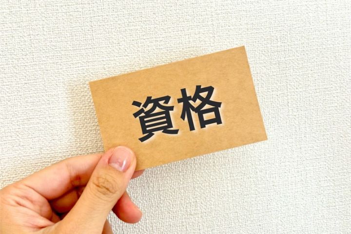 資格と書かれた紙を持つ手元の画像