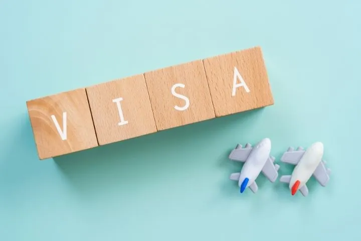 VISAと書かれた木のブロックと飛行機の置物の画像