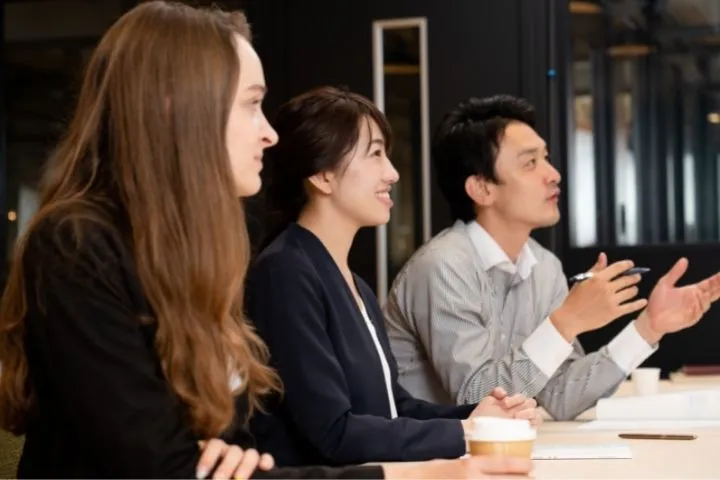 3人の男女が誰かの話を聞いている画像