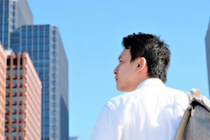オフィス街で考えている男性の横顔の画像