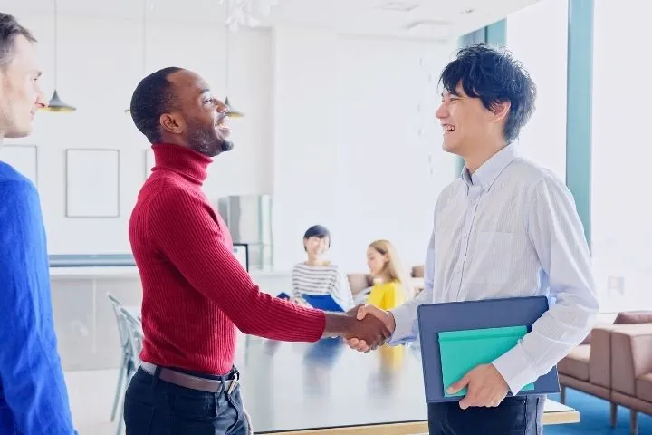 海外企業と契約を結び、笑顔で握手をしている男性エンジニアのイメージ