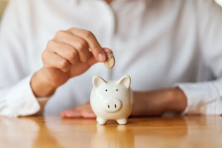 貯金箱に小銭を入れようとしている様子