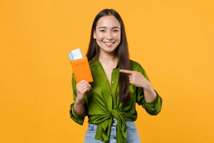 パスポートとチケットを指差す女性のイメージ