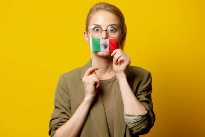 メキシコ国旗で口元を隠す女性の画像