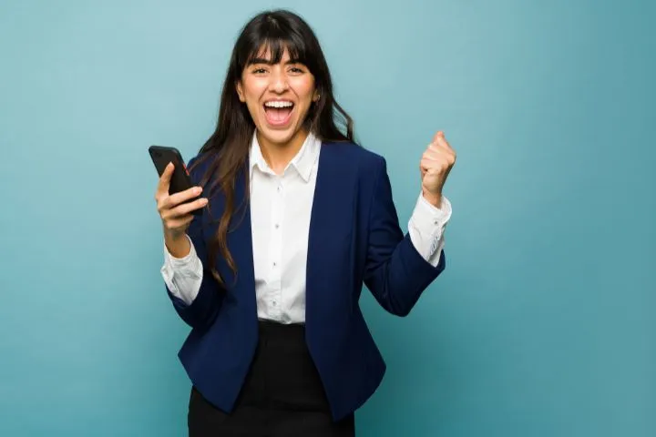 スマホを持ってガッツポーズをする女性の画像
