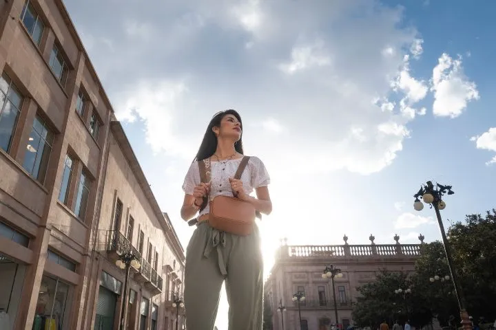 太陽を背にして日没時にメキシコの街を歩く女性のイメージ