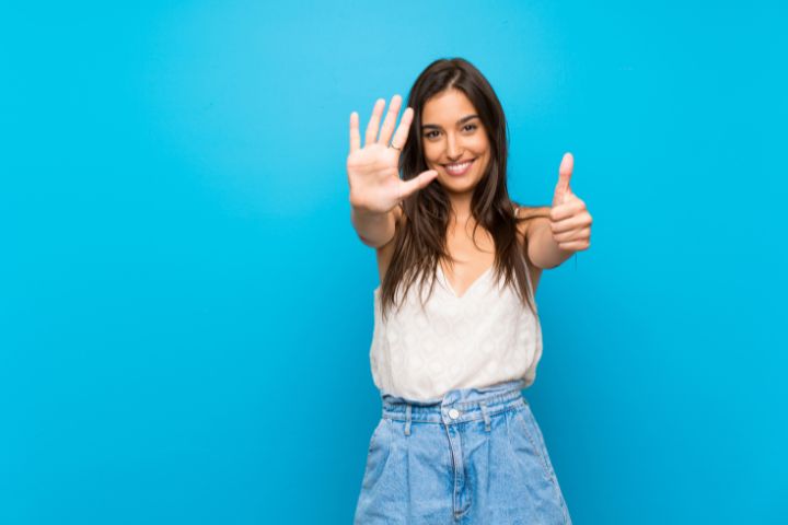 指で６のポーズをとるスパニッシュ系の女性の画像
