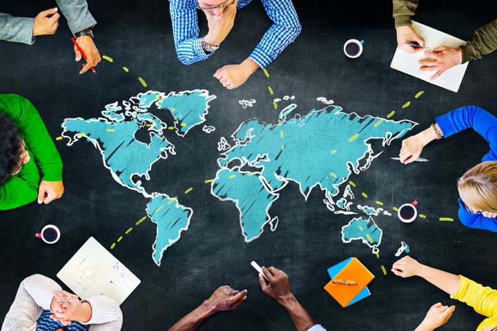 世界地図を数名が囲んで見ている画像