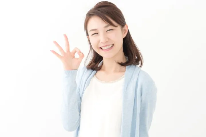 手でOKマークを作る女性の画像