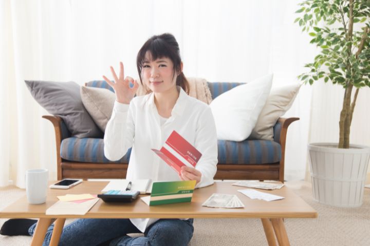 通帳を持ってOKサインを出している人のイメージ