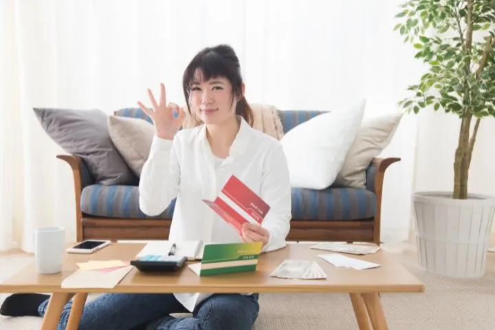 通帳を持ってOKサインを出している人のイメージ