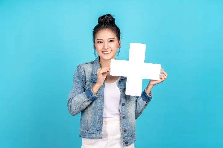 白いプラスマークを持った若いアジア女性の画像
