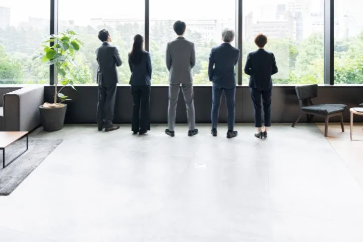 会社から外を眺める人々のイメージ