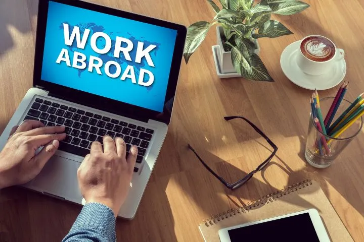 work abroadと表示されたノートパソコンを操作する男性の手の画像