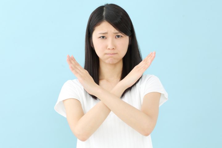 手で×マークを作っている女性の画像