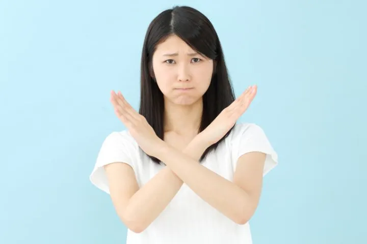 手で×マークを作っている女性の画像