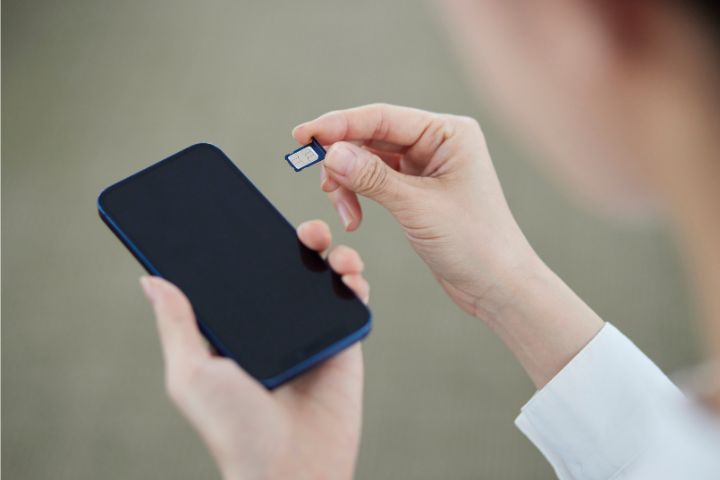 スマートフォンにSIMカードを差し込む女性の手元のイメージ