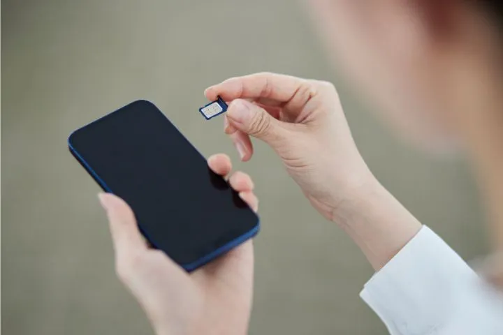 スマートフォンにSIMカードを差し込む女性の手元のイメージ