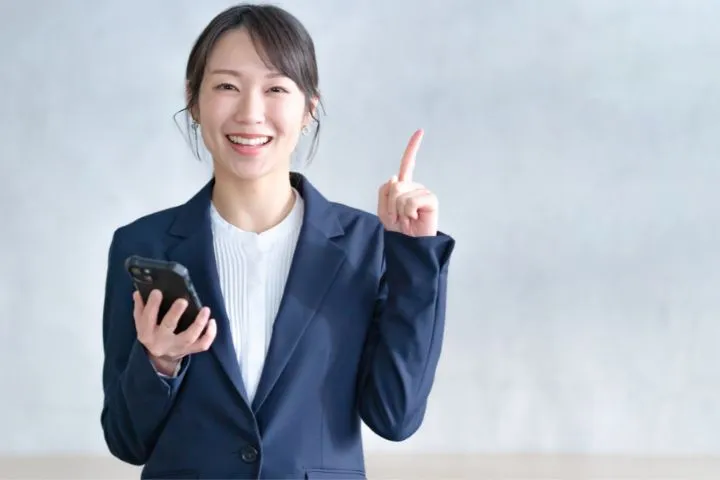 人差し指を立てるスーツ姿の女性
