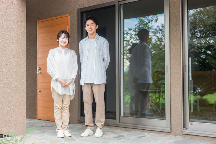 家の前に立つ若い夫婦