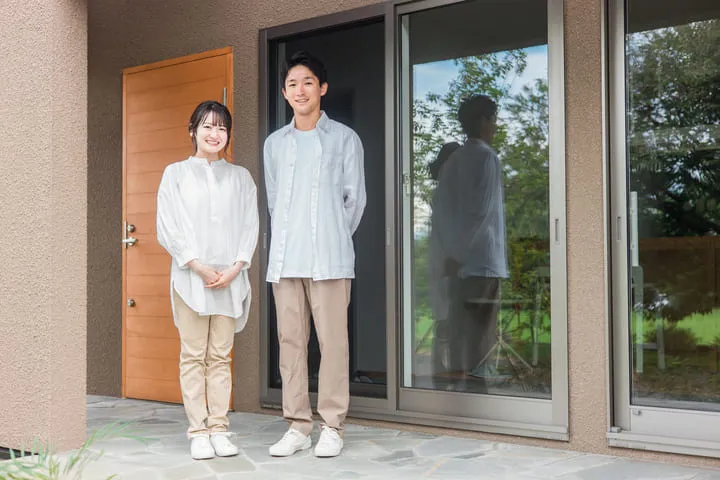 家の前に立つ若い夫婦