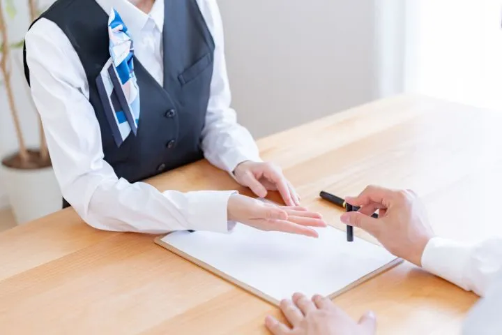 銀行員と手続きをする男性の画像