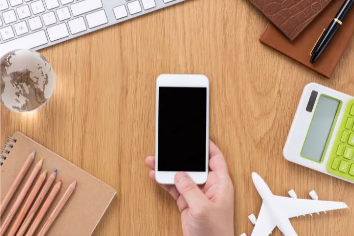 スマホと電卓、地球儀や飛行機の模型の画像