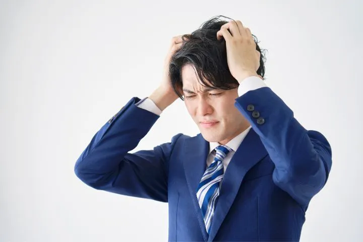 頭を抱えるスーツを着た日本人男性の様子