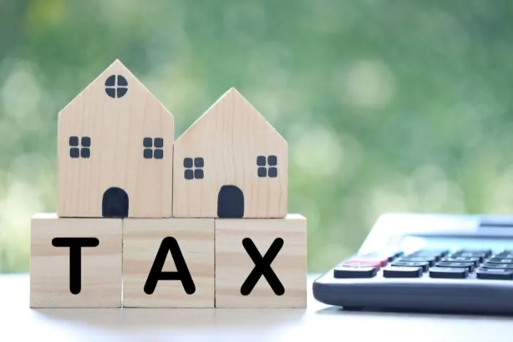 TAXと書かれた積木の上にミニチュアの家が2つ置いてある様子