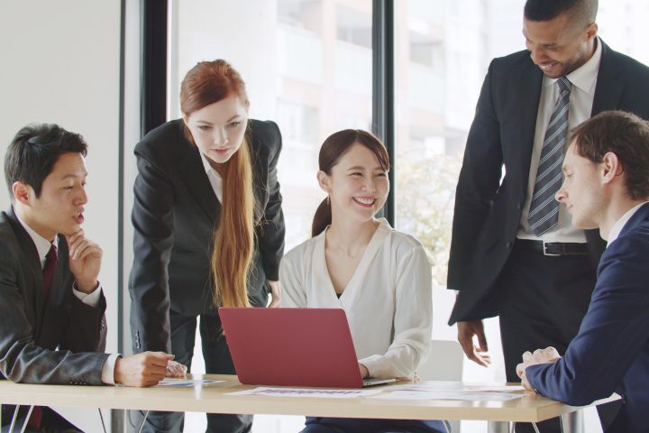 笑顔で外国人のビジネスマン達と話す女性のイメージ