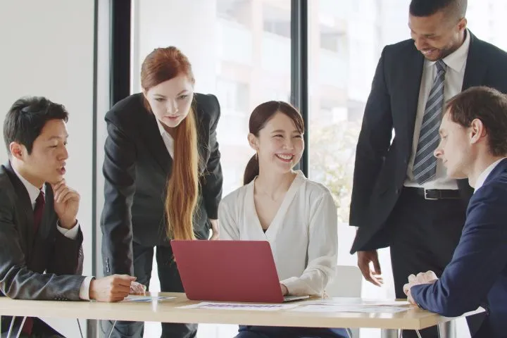 笑顔で外国人のビジネスマン達と話す女性のイメージ