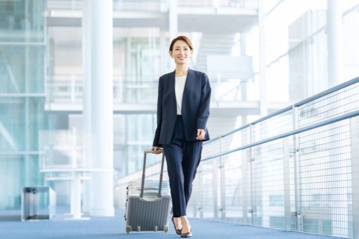 スーツケースを持って空港を歩くビジネスウーマンのイメージ
