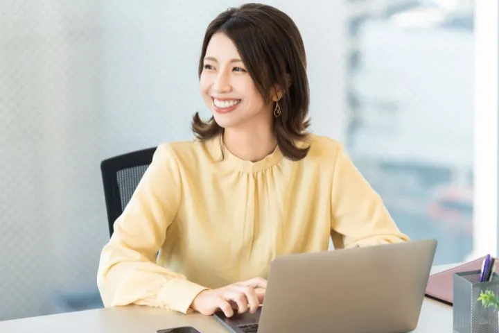 ノートパソコンの前で笑顔の女性のイメージ