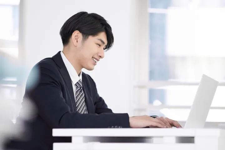 笑顔でパソコンを開くビジネスマンのイメージ