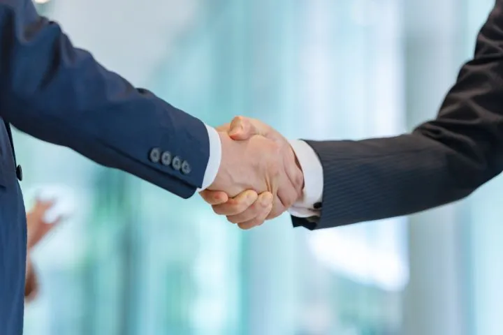 スーツ姿の男性二人が握手している様子