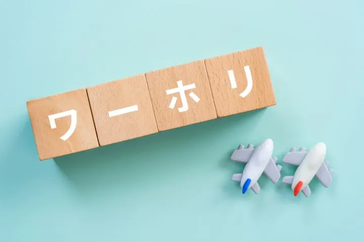ワーホリと書かれた積木とミニチュアの飛行機2機の画像