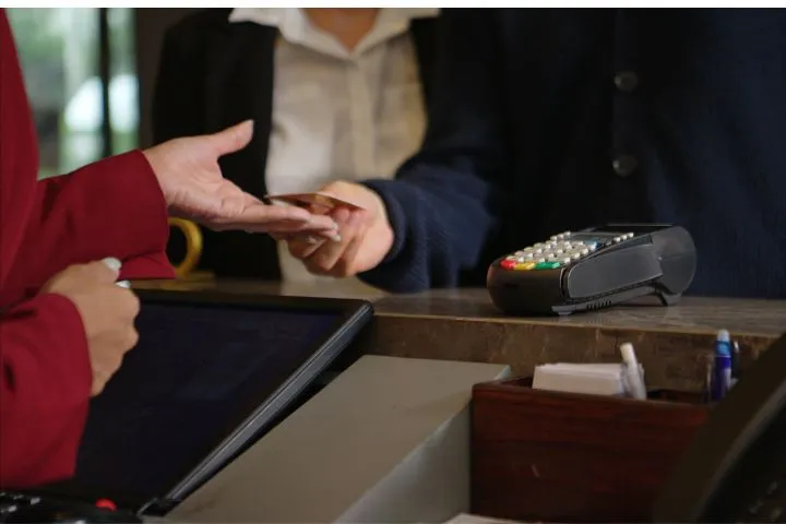 受付でクレジットカードを渡す客の画像