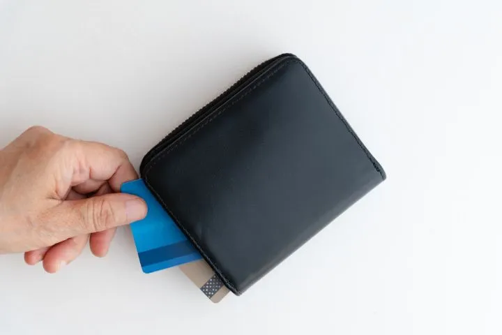 財布の中にあるクレジットカードを取り出す手の画像