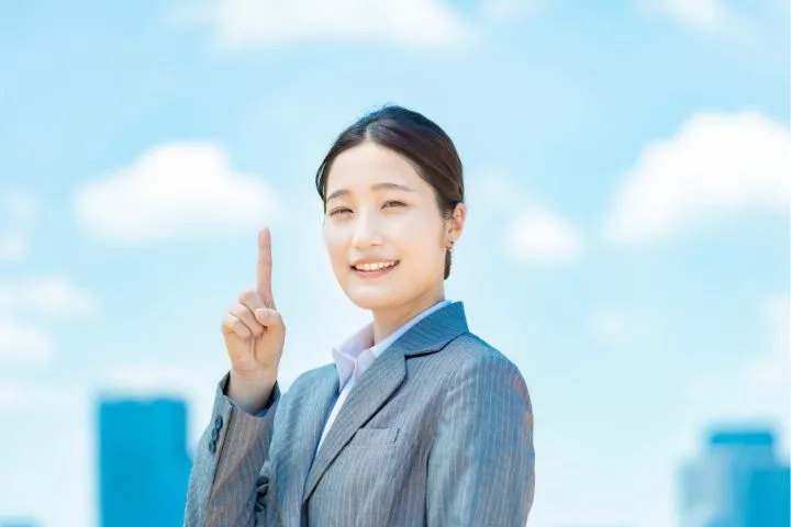 人差し指を立ててほほ笑む女性の画像