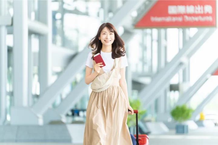 パスポートを持った女性が空港にいるイメージ