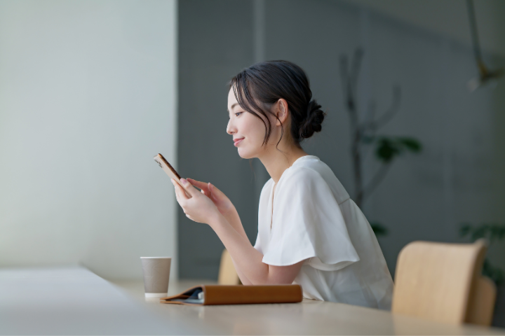 カフェでスマホを眺める女性の画像