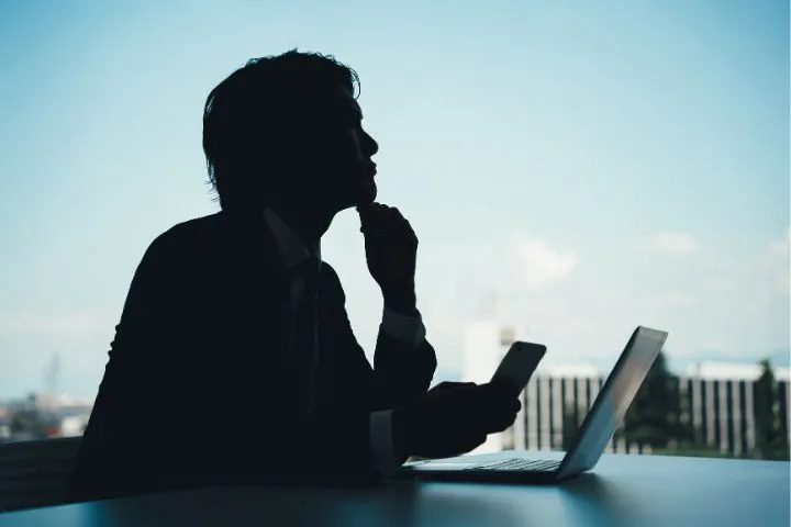 ノートパソコンを開き考える男性のイメージ