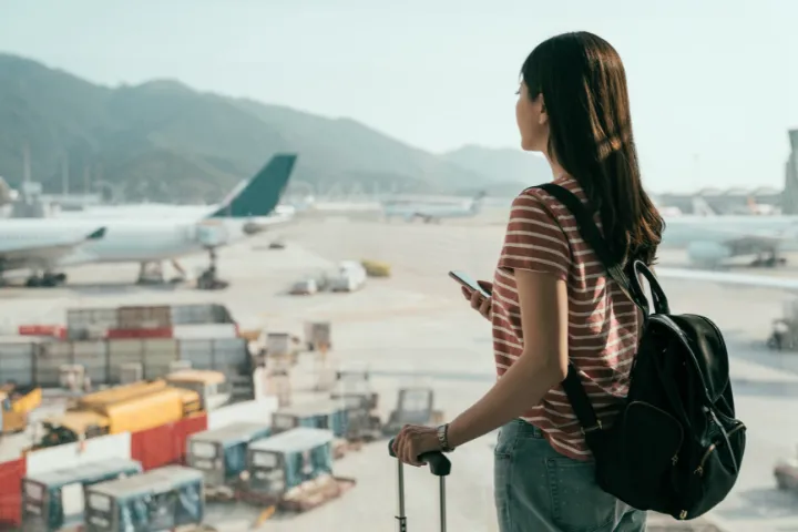 空港で飛行機を眺める女性観光客の後ろ姿の画像