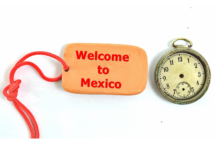 ようこそメキシコへと英語で書かれたタグと針のない時計が置かれた画像
