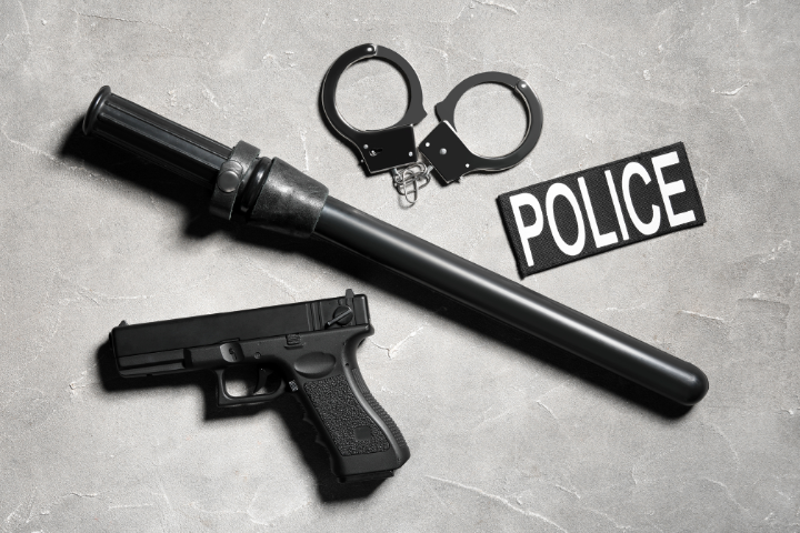 拳銃、警棒、手錠、POLICEと書かれた紙が並んでいるイメージ