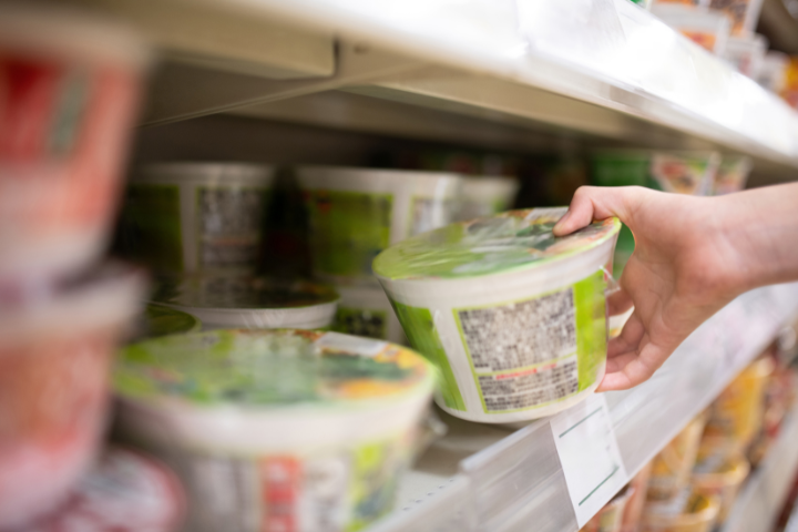 売り場の棚からカップラーメンを手に取っている画像