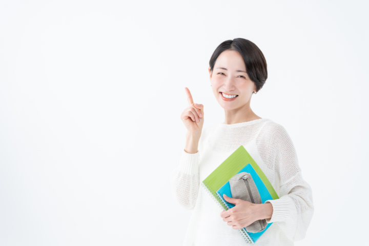 ノートや筆記用具を持った女性が指をさしているイメージ