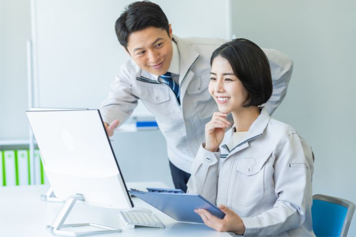 事務作業する作業服姿の女性と男性のイメージ