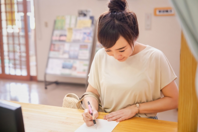 カウンターで紙に書いている女性の画像