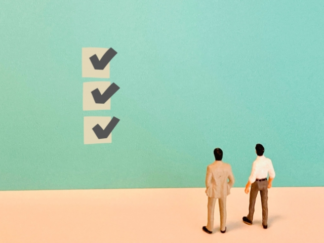 チェックマークを見る2体の人形の後ろ姿の画像